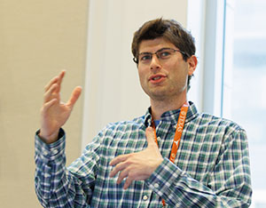 symposium panelist speaking at podium and gesturing with hands